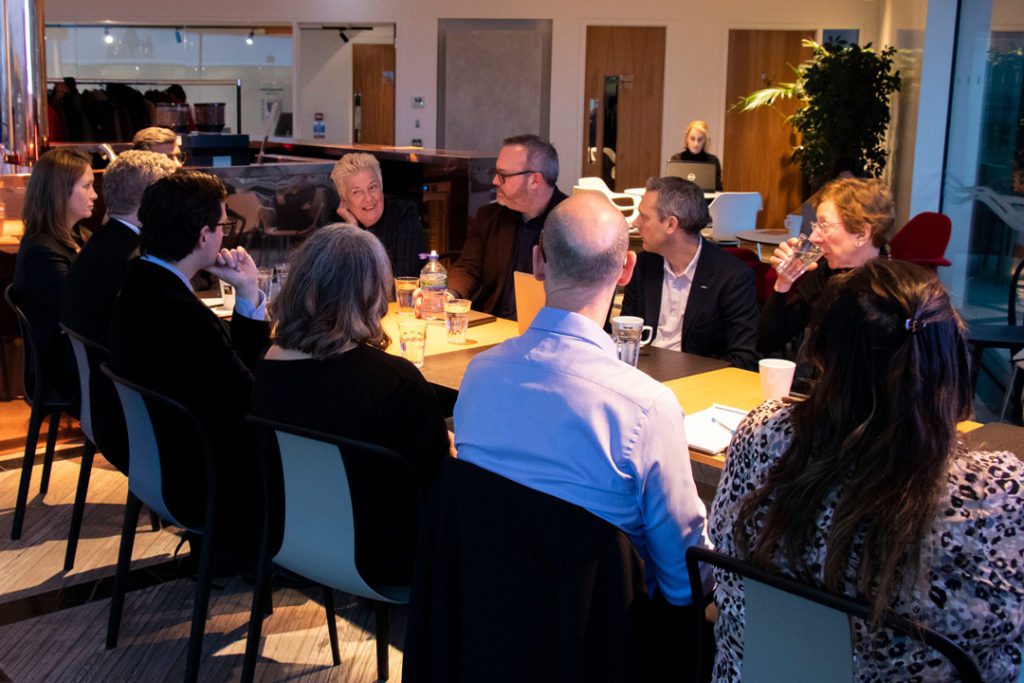 Boardroom meeting, staff sat around table discussing plans.