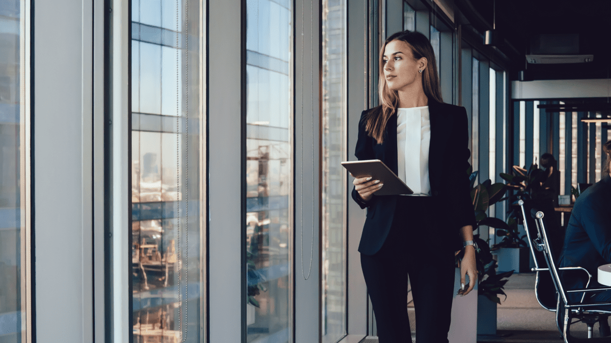 Header image of a woman walking in an office holding an ipad