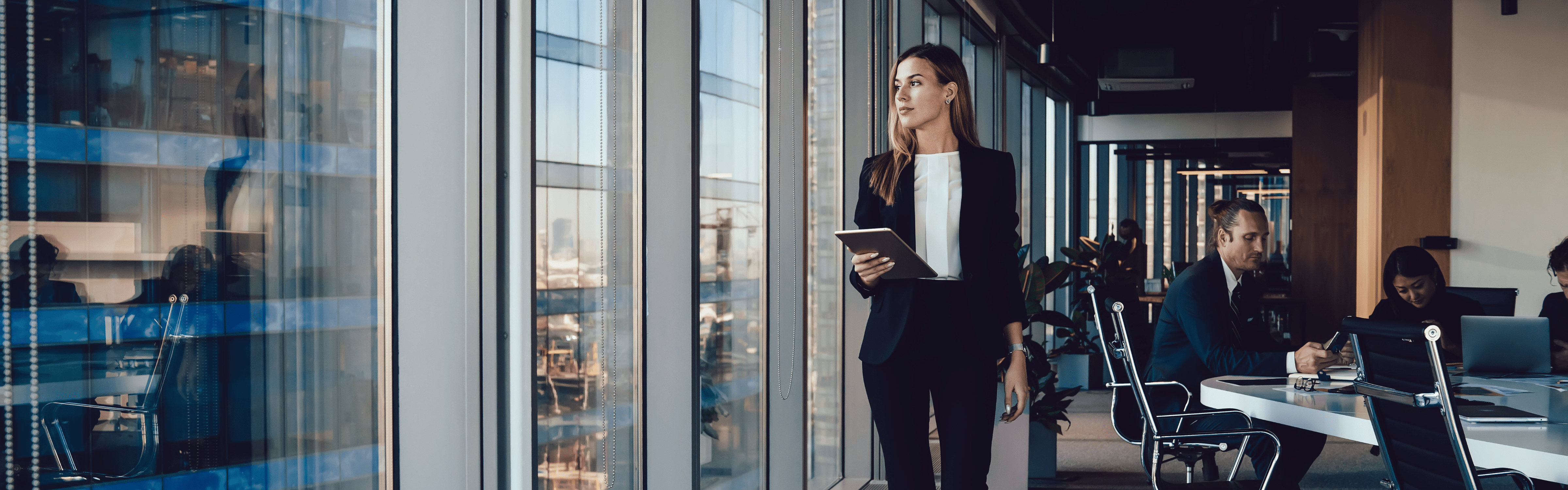 Header image of a woman walking in an office holding an ipad